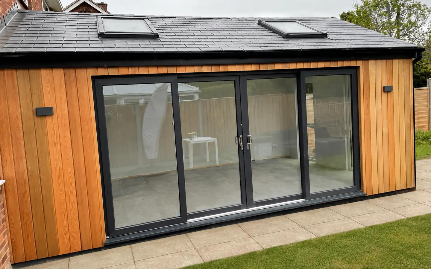 Timber-clad garden room with a tiled roof, two rooflights and dark-framed glazed doors